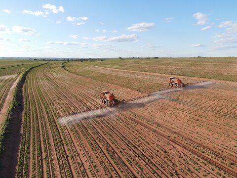 Imagem aérea de tratores em ambiente agrícola durante pulverização da lavoura.