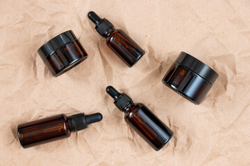 Cometic bottles made of amber glass on crumpled craft paper. Skin care products packaging design. Spa concept.