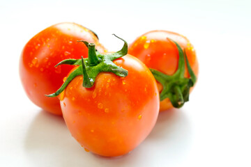 Fresh tomatoes on white wooden table in sunlight.