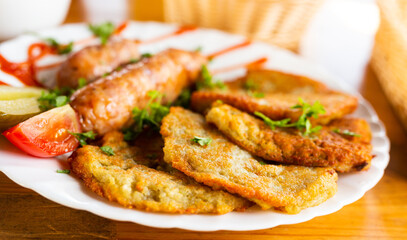 potato pancakes with fried sausages on a white plate