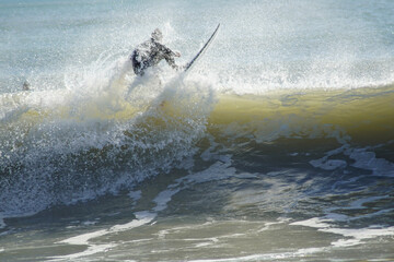 Obraz premium Joven practicando surf sobre una ola