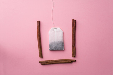 Tea bag in a cup of cinnamon on a pink background