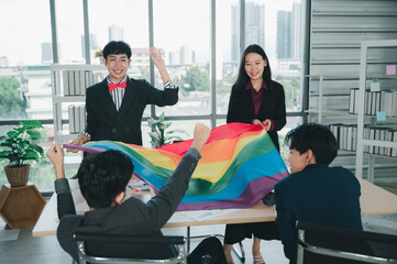 Group of LGBTQ businessmen with a rainbow flag in hand are having fun with their colleagues inside the office. The concept of diversity, race and culture, the concept of anti-sexism.