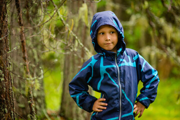 a boy in a blue jacket walks in the woods, a selective focus