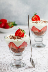 Layered Dessert of chocolate sponge cake, whipped cream or ricotta and fresh strawberries in a glass bowl. Trifle.  Delicious gourmet breakfast. Selective Focus, copy space