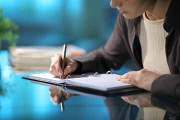 Woman hands taking notes in a ring binder notebook in the night