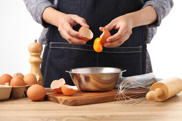 Woman hands to separate egg white and yolks with egg shells