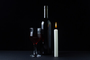 Wine and candle on a dark background. Creative photo of red wine on a black background. Wine by candlelight