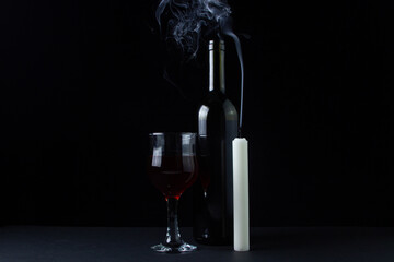 Wine and candle on a dark background. Creative photo of red wine on a black background. Wine and candle smoke