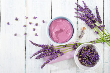 cosmetic cream, soap and purple lavender flowers on white wooden, top view