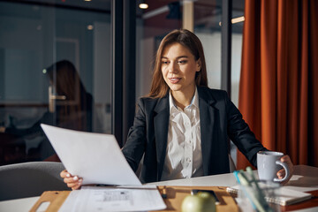 Focused draftswoman studying a technical drawing in her hands