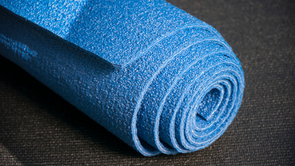Esterilla de yoga azul enrollada sobre esterilla negra