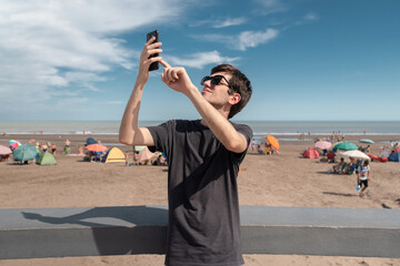 Young man on the coast looking for signal on his smart phone. Concept of connectivity and connection problems.