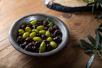 Natural black and green olives with rosemary, basil and olive tree leaves.