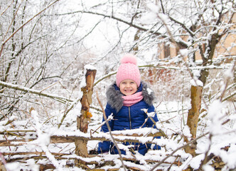 A girl in a pink hat plays with snow. Holidays with a child in winter