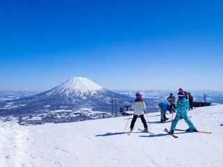 Skiers looking at snowy volcano on a clear day in early spring (Niseko Hanazono Resort, Hokkaido, Japan)