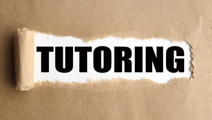 TUTORING.text on white paper over torn paper background.