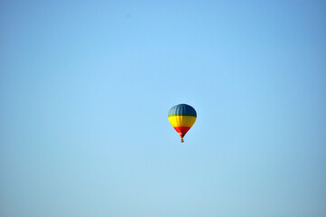 Close-up of a large hot air balloon with stripes of different colors on a background of blue sky.