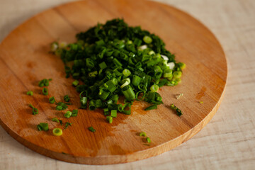 Large horizontal photo. Fresh green dill on a round wooden board. Summer time. Vitamins. Eco. Proper nutrition, healthy lifestyle. The process of cutting vegetables.