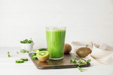 Glass of tasty green smoothie and ingredients on light background