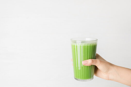 Woman Holding Glass Of Tasty Green Smoothie On Light Background