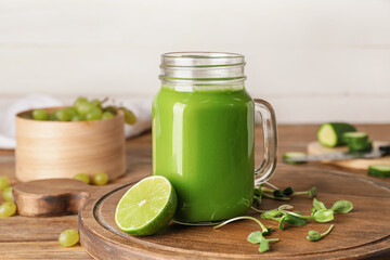 Mason jar of healthy green smoothie and ingredients on wooden background
