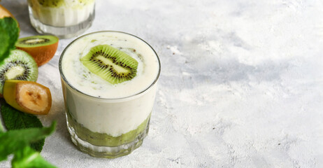 Yogurt with kiwi in a glass. Fruit and berry smoothie. Milkshake with kiwi and banana. Healthy eating. Light background. Copy space.