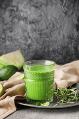 Glass of healthy green smoothie and ingredients on dark background