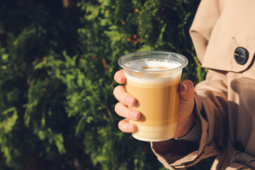 Woman drinking tasty latte outdoors, closeup