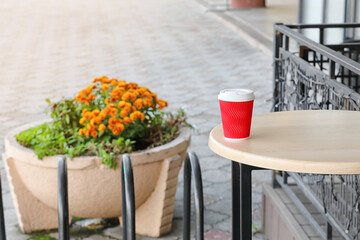 Takeaway cup of tasty latte on table outdoors