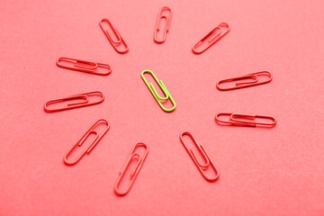 Yellow paper clip among red ones on color background. Concept of uniqueness