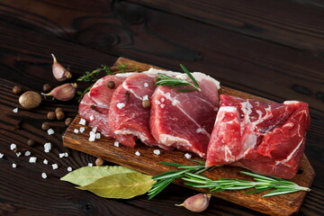 Fresh raw meat sliced with seasonings and spices on a wooden board.