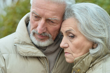 Sad thoughtful senior couple in  park