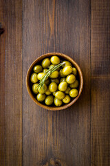 Wooden bowl of pickled green olives, top view