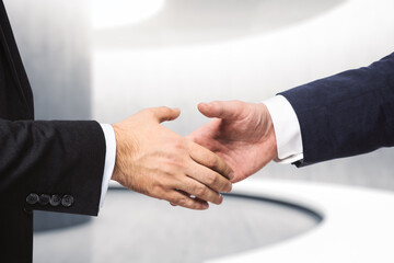 Obraz premium Two businessmen shake hands on the background of empty modern office, signing of a contract concept, close up