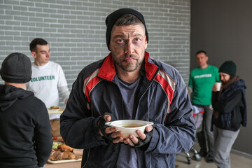 Poor homeless man with hot food in warming center