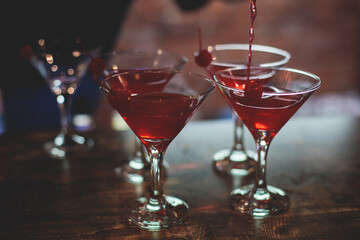 View of different coloured alcohol beverage cocktail drinks setting on bar counter in the night club party, tequila, glasses with martini, vodka, spritz and others on decorated catering banquet table