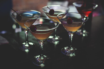 View of different coloured alcohol beverage cocktail drinks setting on bar counter in the night club party, tequila, glasses with martini, vodka, spritz and others on decorated catering banquet table