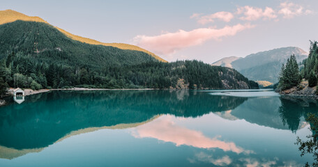 Naklejka premium Panorama of the sun rising over the calm turquoise blue waters of Diablo Lake in North Cascades National Park, Washington, USA.
