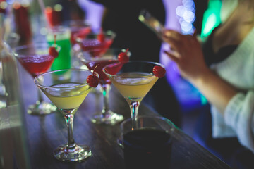 View of different coloured alcohol beverage cocktail drinks setting on bar counter in the night club party, tequila, glasses with martini, vodka, spritz and others on decorated catering banquet table
