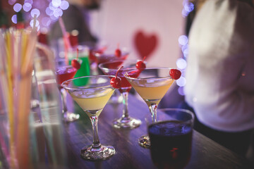 View of different coloured alcohol beverage cocktail drinks setting on bar counter in the night club party, tequila, glasses with martini, vodka, spritz and others on decorated catering banquet table