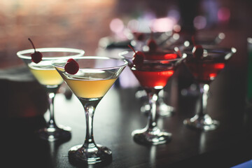 View of different coloured alcohol beverage cocktail drinks setting on bar counter in the night club party, tequila, glasses with martini, vodka, spritz and others on decorated catering banquet table