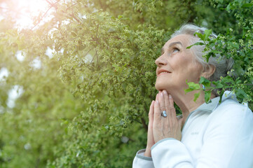 Senior woman praying in park