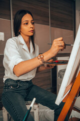 Beautiful talented female artist painting at her home.