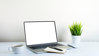 Laptop computer blank screen on white office desk table with coffee cup and notebook, mouse...