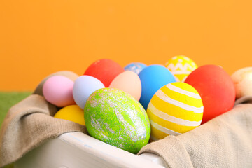 Box with beautiful Easter eggs on color background, closeup
