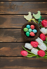 colorful tulips and Easter eggs on brown wooden surface