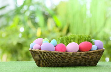 Basket with beautiful Easter eggs on grass outdoors