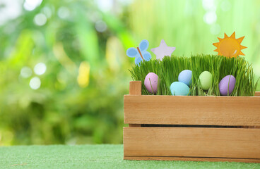 Box with beautiful Easter eggs on grass outdoors