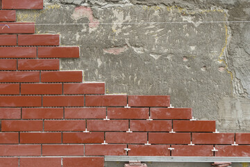 Wall or fence decoration. Laying decorative tiles for red bricks on a vertical surface - 422549113